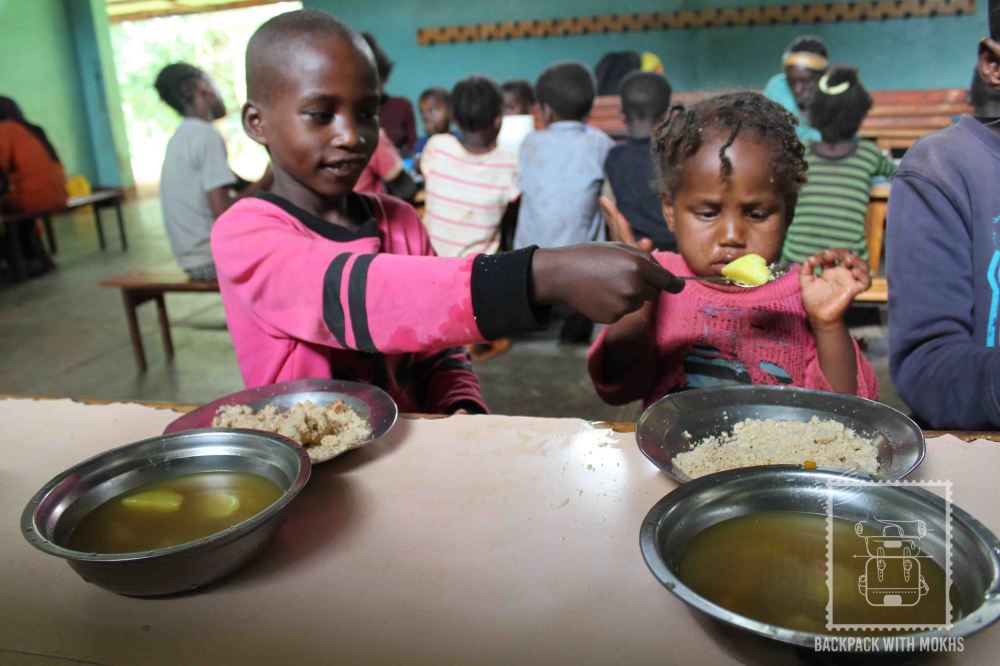 elder sister helping her younger one eat food