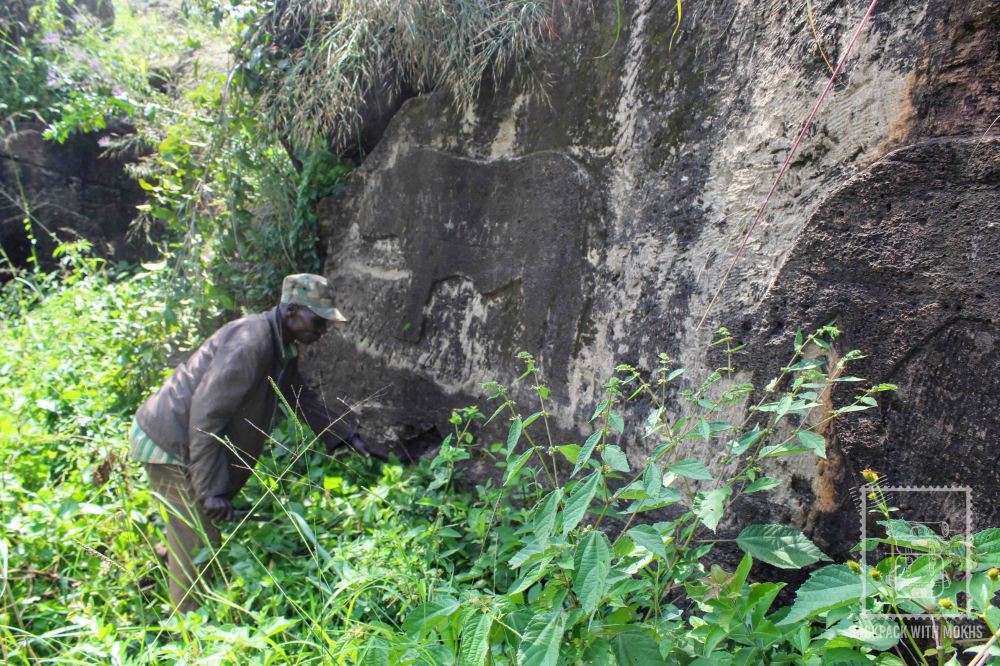 man removing grass from infront of the carvings